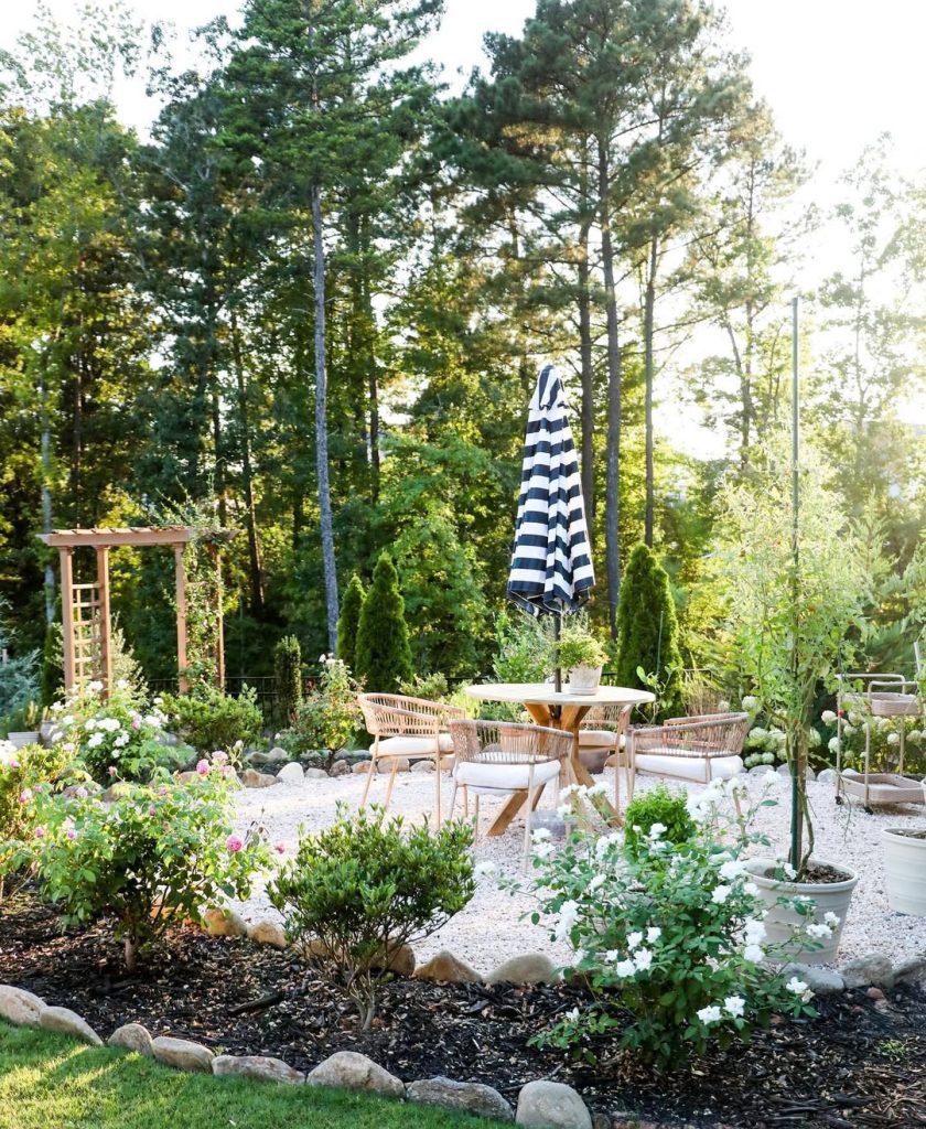 Garden dining area with rattan furniture white flowers and pine trees