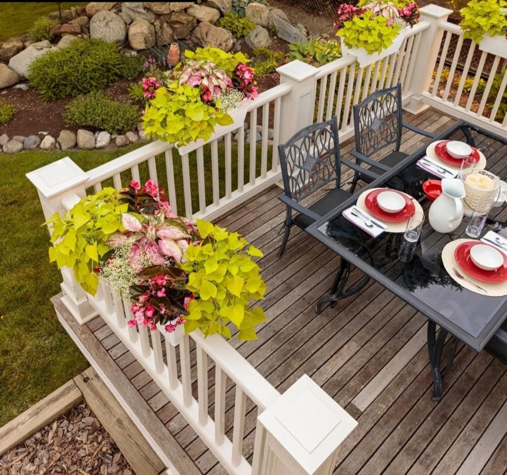 Deck dining area with white railings planters and black furniture