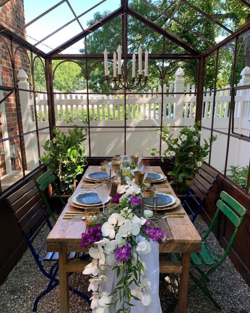 Greenhouse dining room with rustic table floral arrangements and colorful chairs