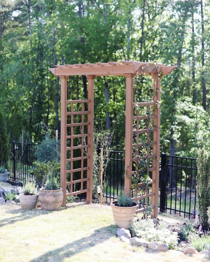 Wooden garden arbor with climbing plants and potted flowers