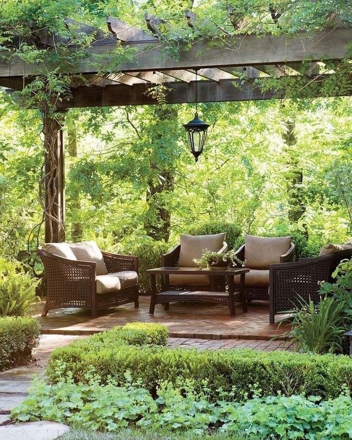 Garden seating area under wooden pergola with wicker furniture and greenery