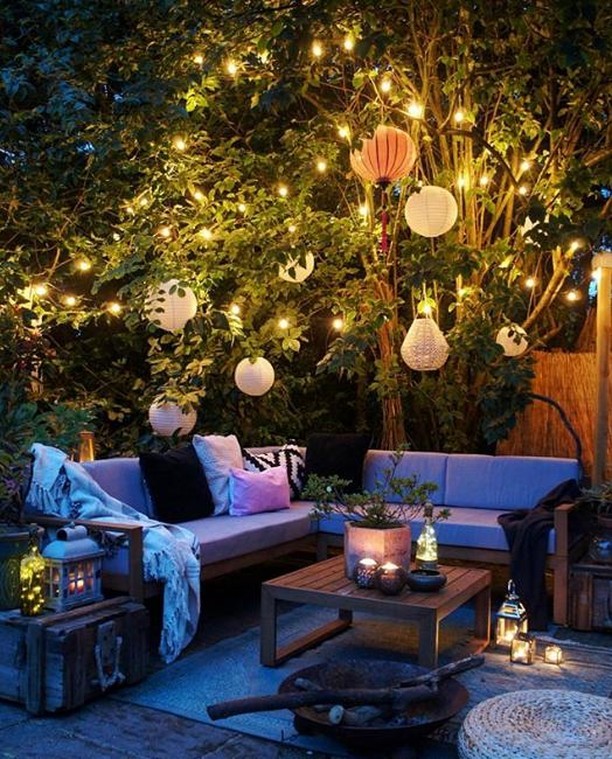 Garden lounge with lanterns string lights and cushioned seating