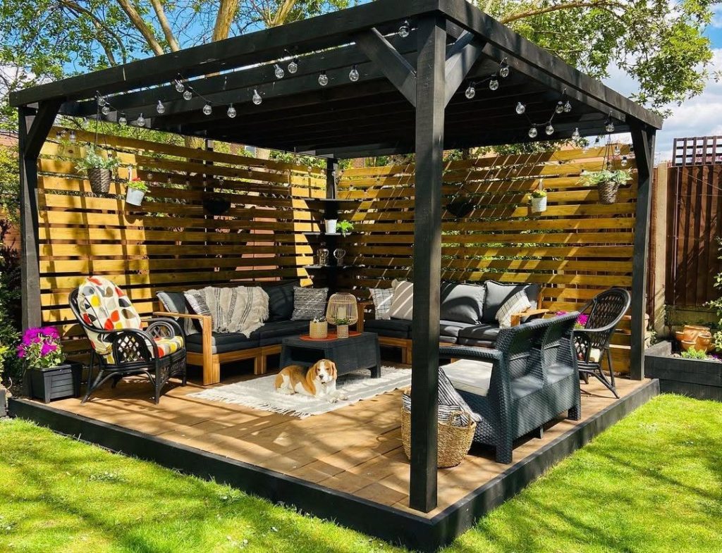 Black pergola with wood screens outdoor furniture and string lights