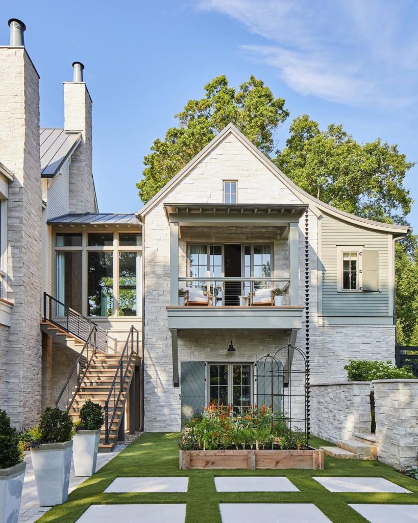 White stone house with balcony and raised garden beds