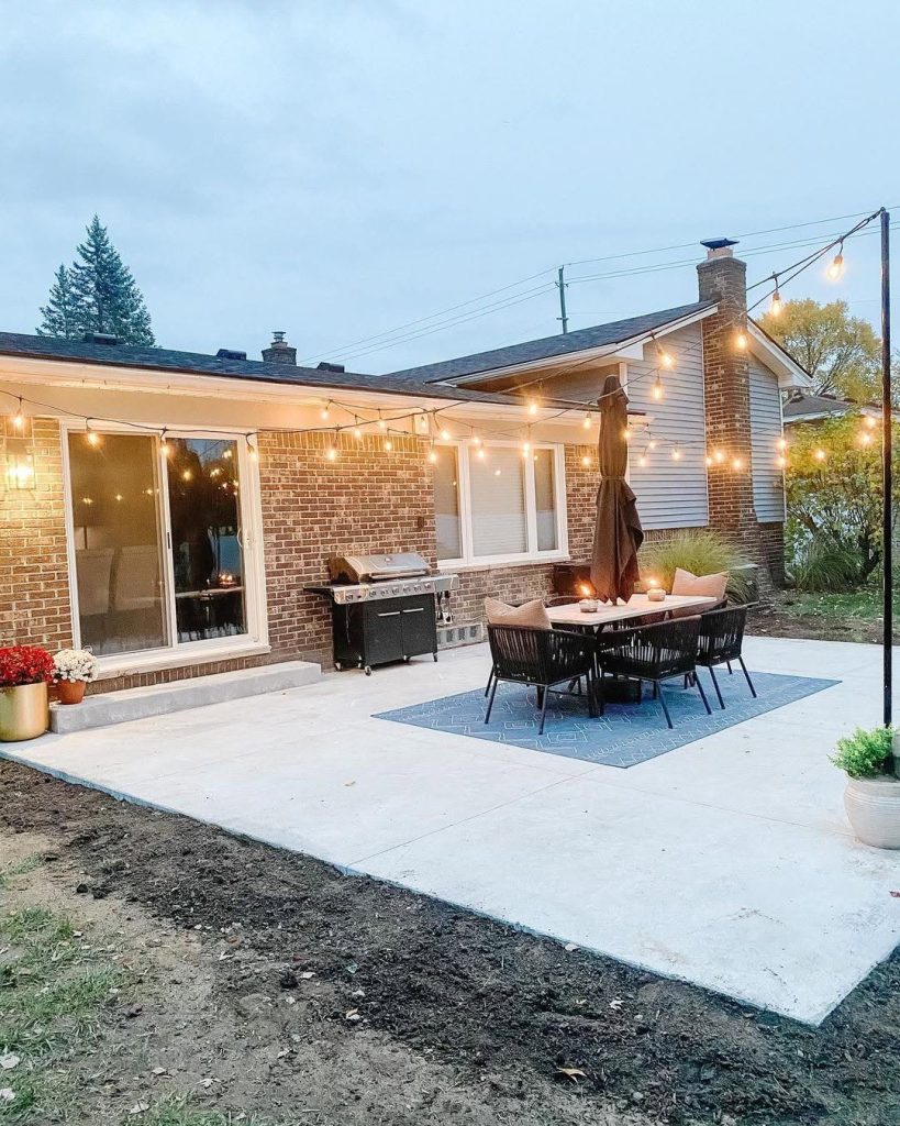 Backyard patio with string lights black furniture and concrete foundation