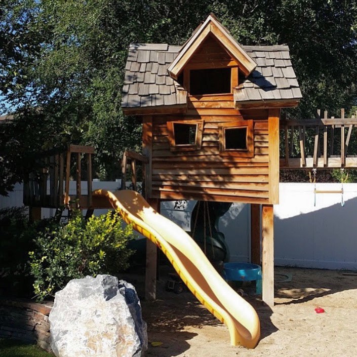 Wooden tower playhouse with yellow slide and rustic finish