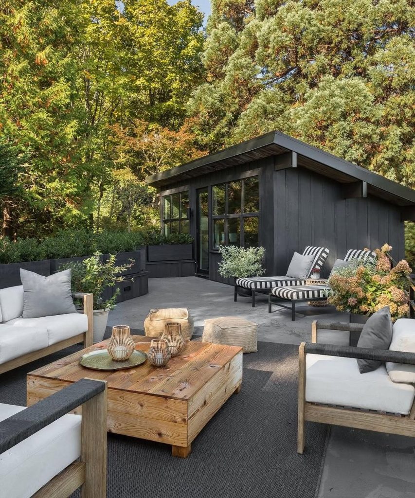 Modern deck with wooden furniture and black shed backdrop