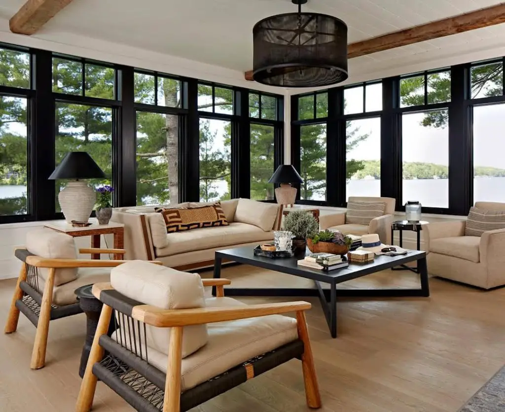 Contemporary lakeside sunroom with black windows cream furniture and wooden beams