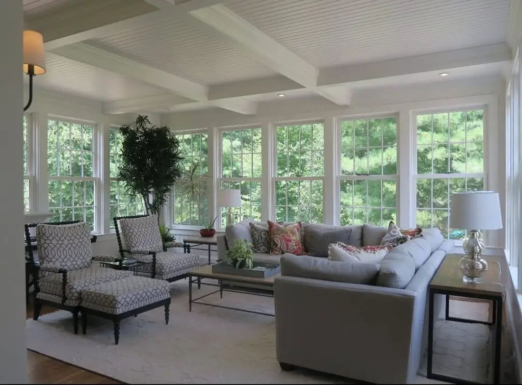 Elegant sunroom with coffered ceiling patterned chairs and large windows