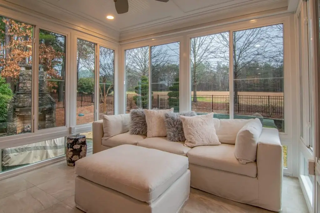 Modern sunroom with cream sectional stone walls and golf course views