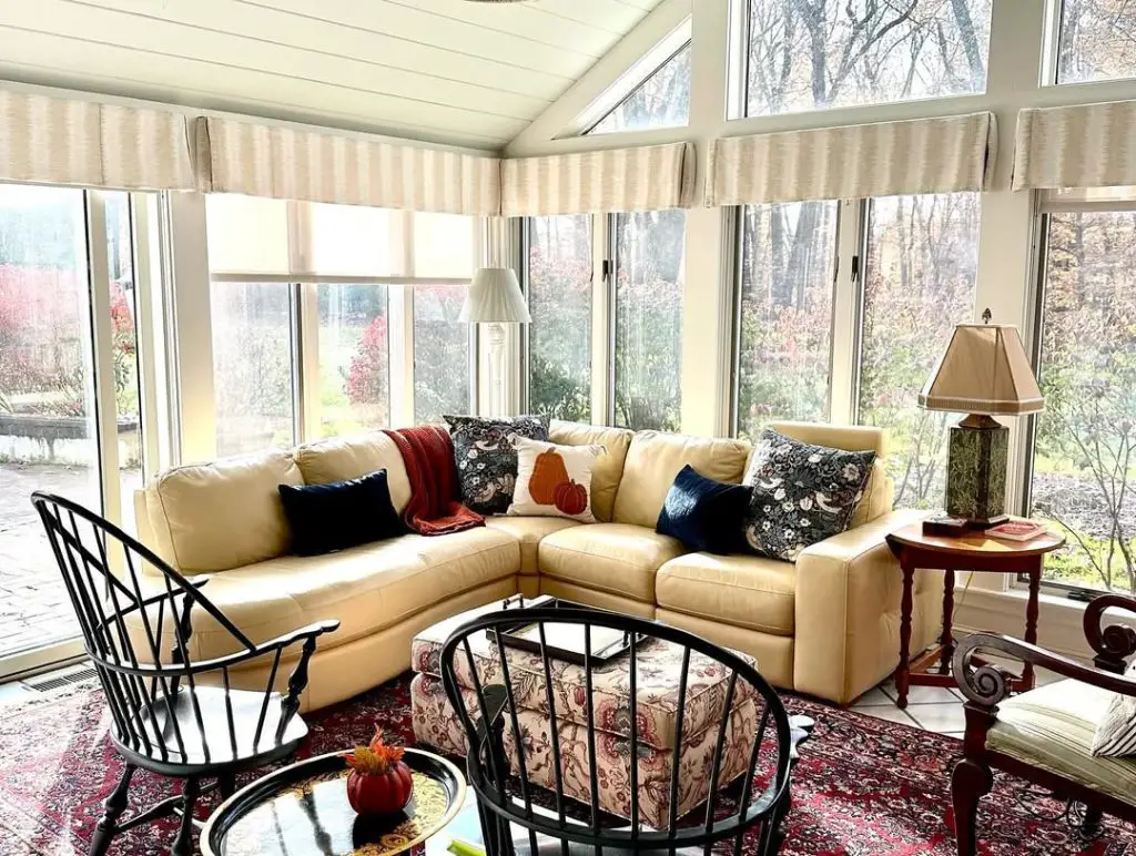 Traditional sunroom with Windsor chairs cream sectional and autumn views