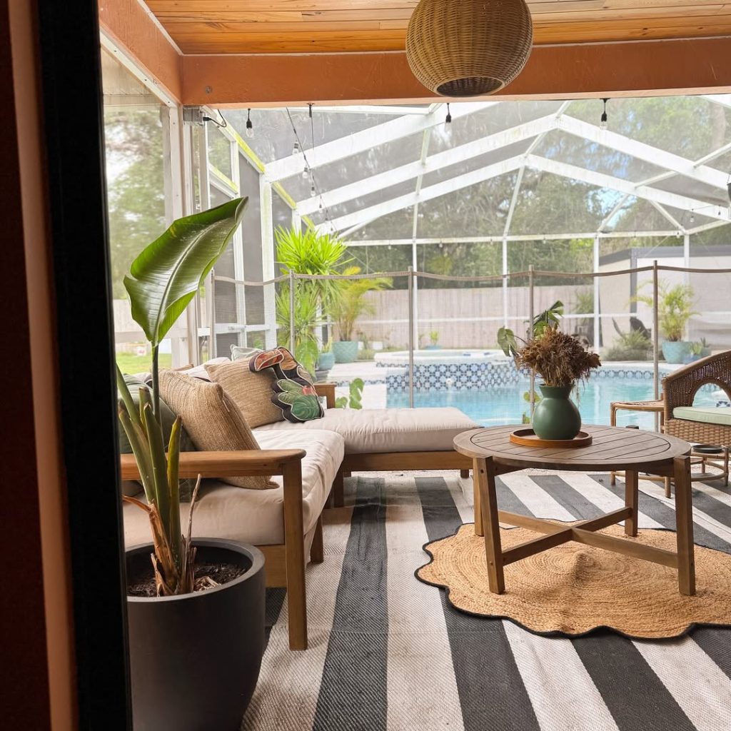 Pool view sunroom with modern furniture striped rug and tropical plants