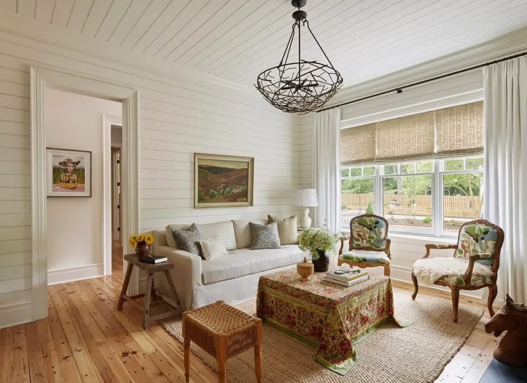 Country style sunroom with shiplap walls white sofa and botanical chairs