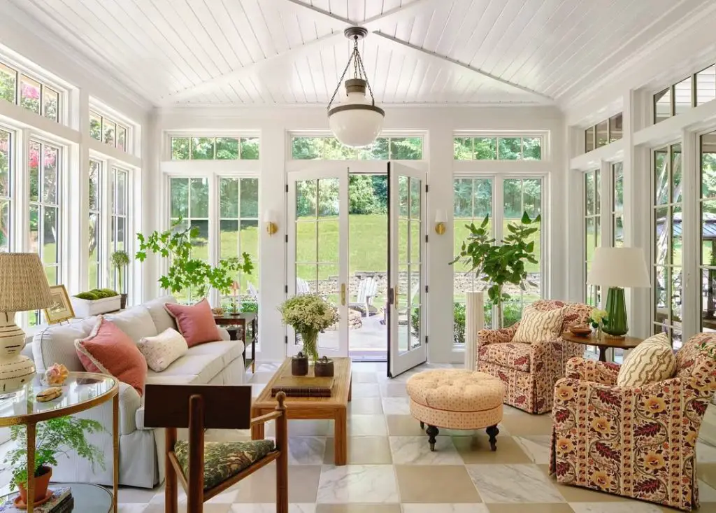Bright sunroom with floral chairs marble floors and garden views