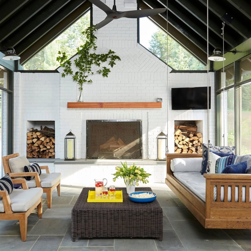 Modern sunroom with white brick fireplace teak furniture and wood storage