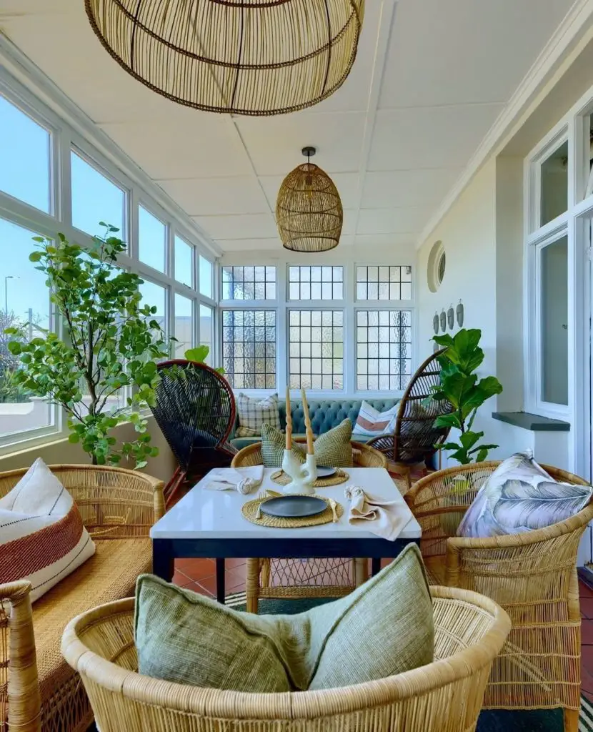 Sunroom dining area with rattan furniture woven lights and greenery