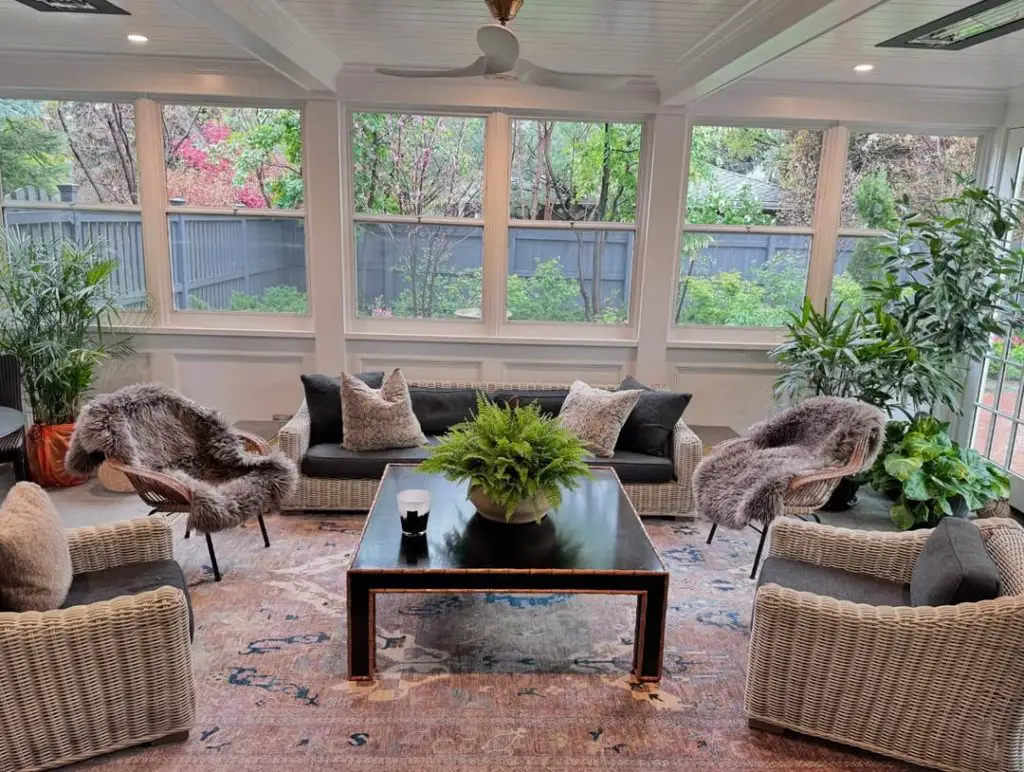 Scandinavian style sunroom with wicker furniture fur throws and black accents
