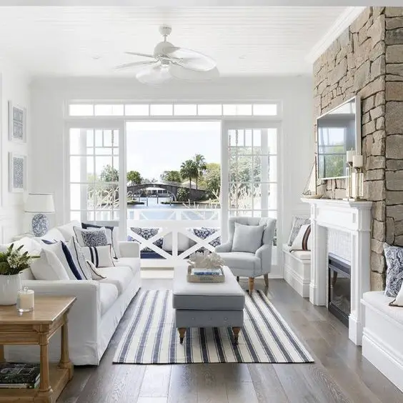 Hampton style sunroom with white furniture blue accents and stone fireplace