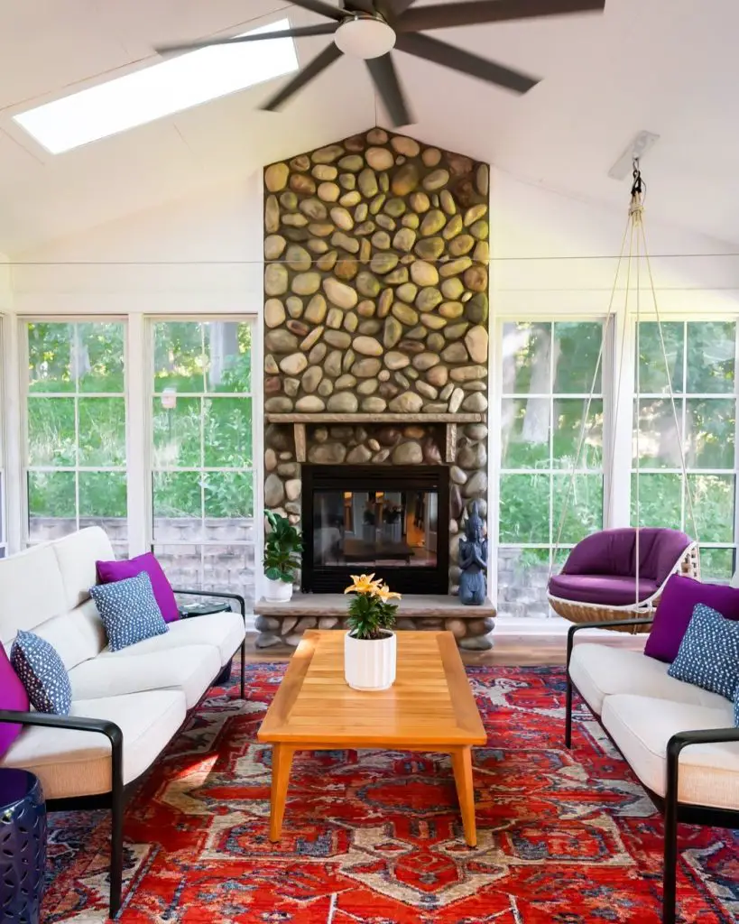 Sunroom with stone fireplace white sofas and purple accents