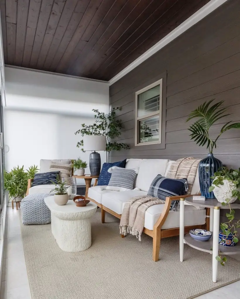 Coastal style sunroom with white sofa navy accents and natural decor
