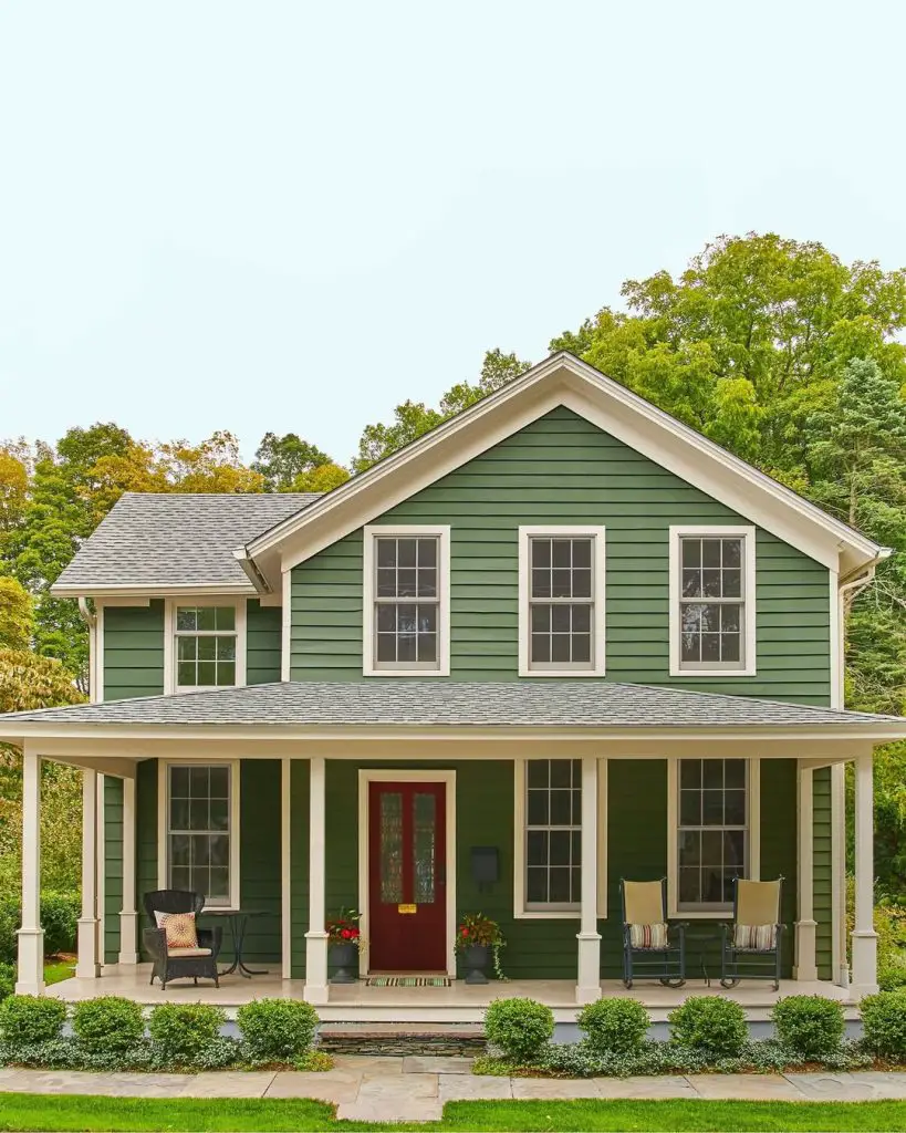 Green farmhouse with white trim wraparound porch