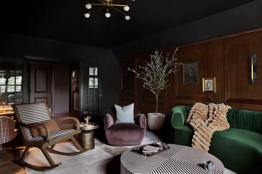 Dark traditional living room with green velvet sofa and wood paneling