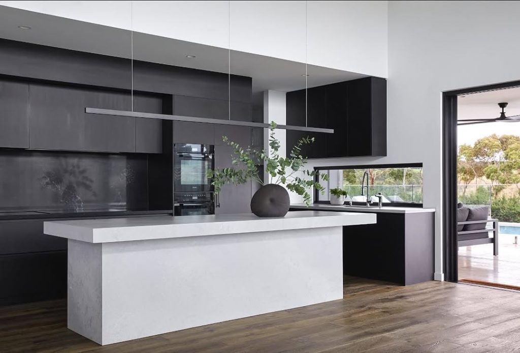 Contemporary kitchen with dark cabinets, white countertops, and large windows