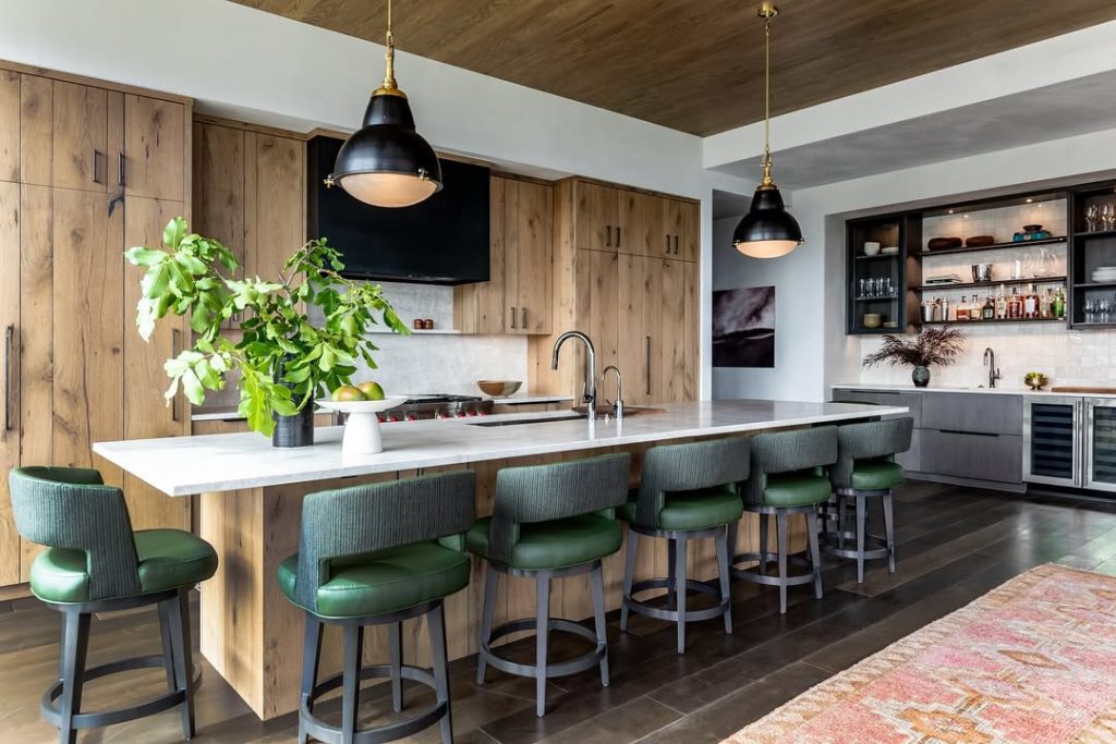 Modern kitchen with wood cabinets, green bar stools, white countertops, black pendant lights
