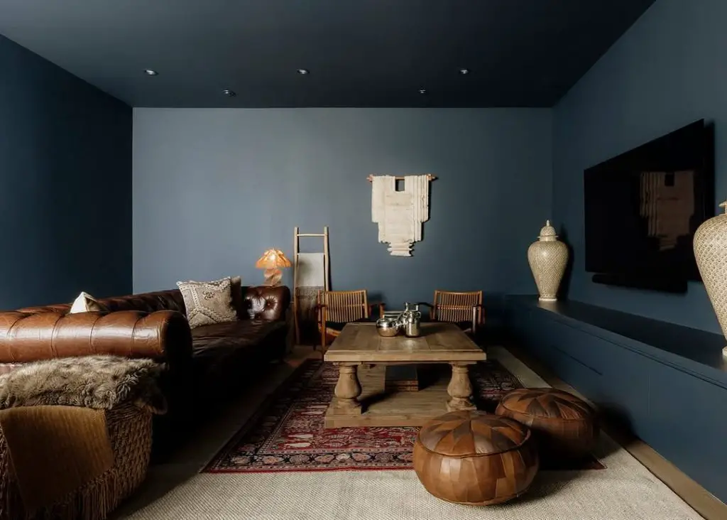 Brown leather sectional with navy ceiling, wooden furniture, Moroccan accents