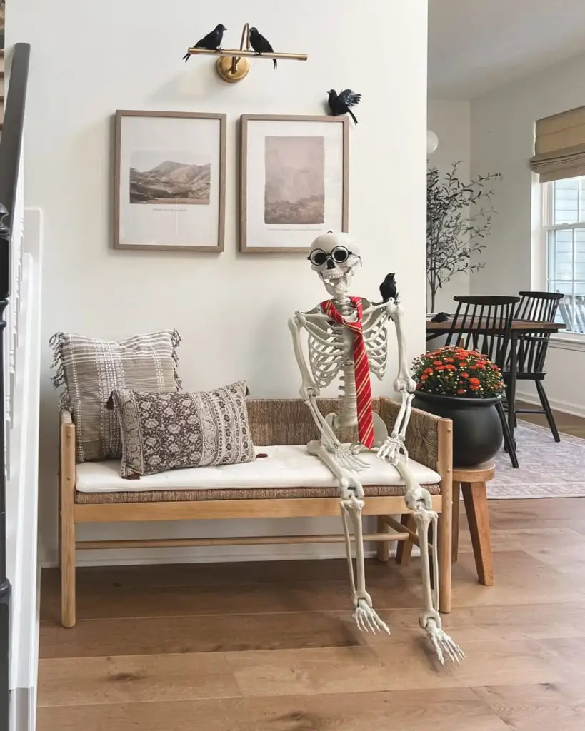 Skeleton decoration sitting on wooden bench with ravens and artwork