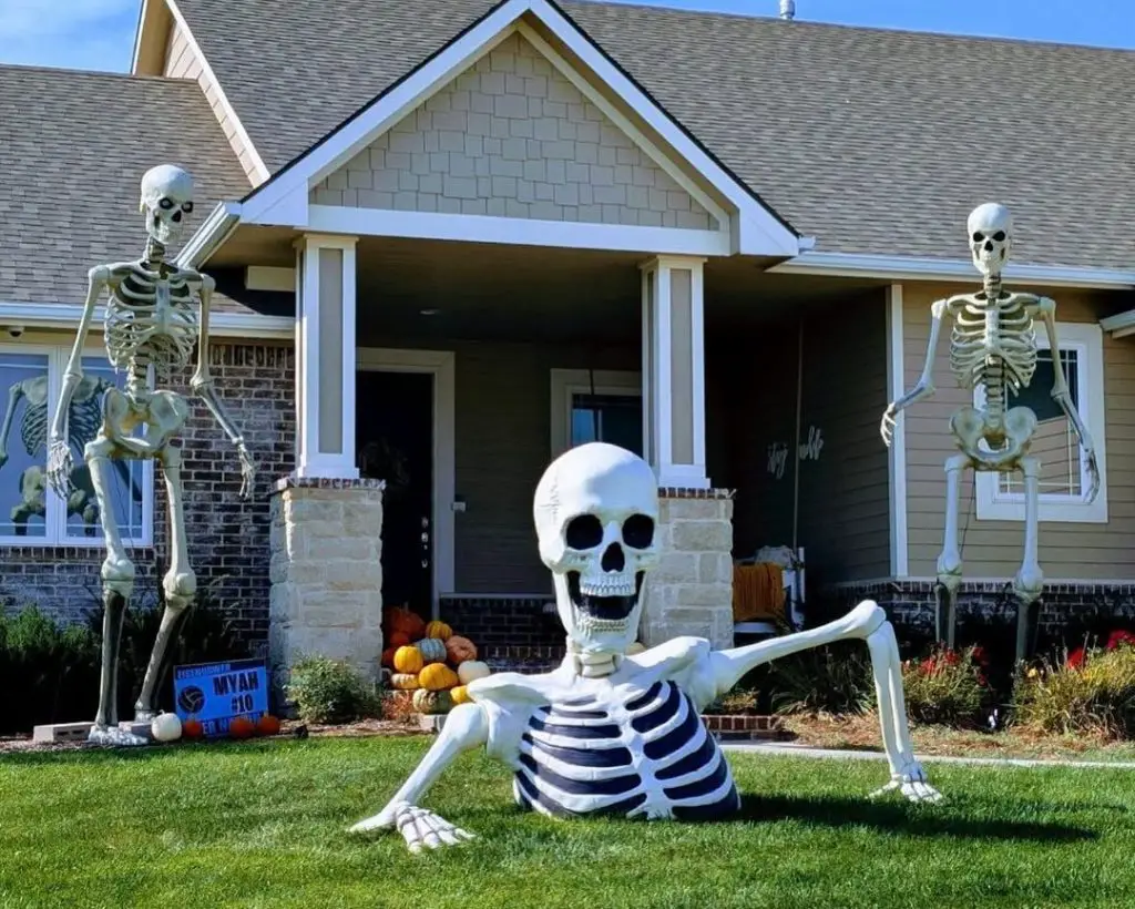 Large skeleton decorations arranged dramatically across front yard and porch