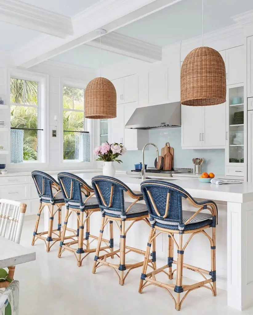White coastal kitchen with wicker pendants and blue bar stools