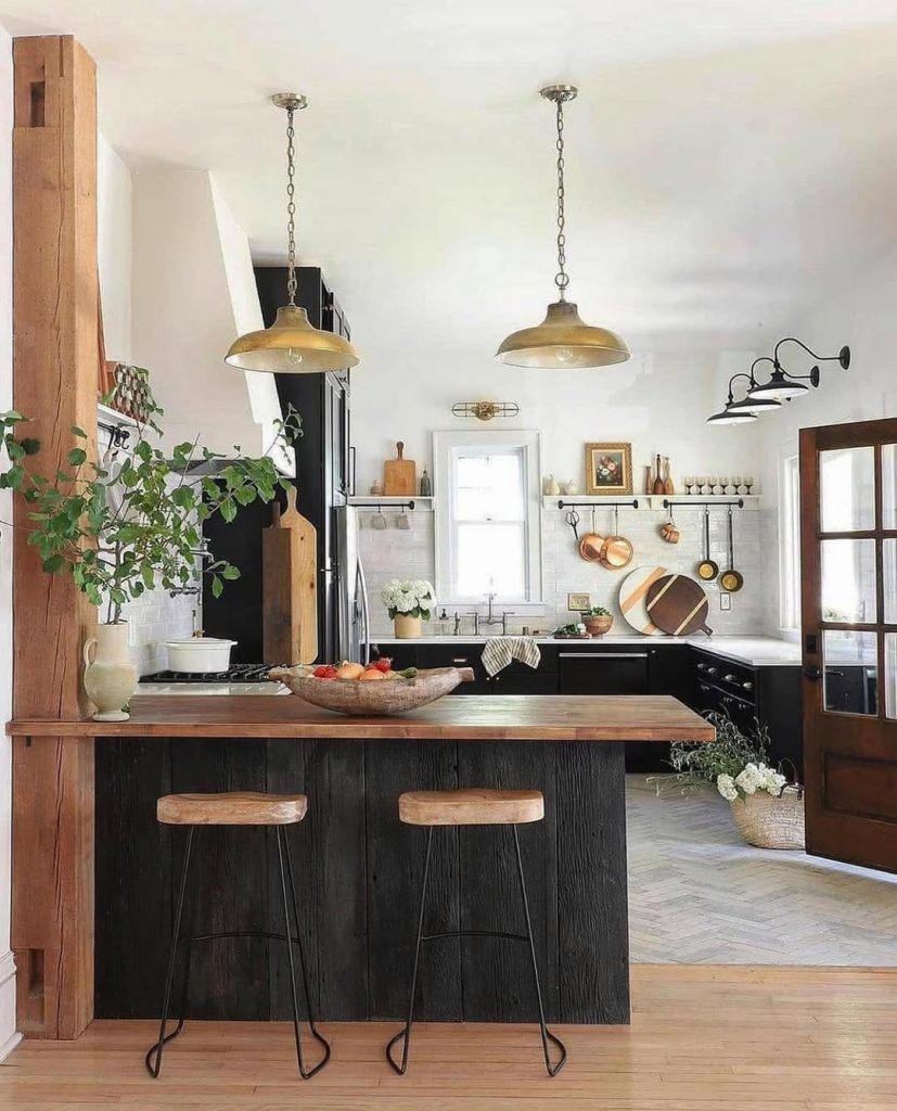 Farmhouse kitchen with copper pendant lights, black cabinets, wood countertops, subway tiles