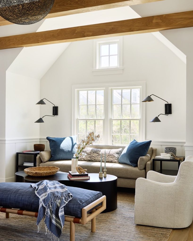 Modern farmhouse living room with wood beams, neutral sofa, blue pillows, and black sconces