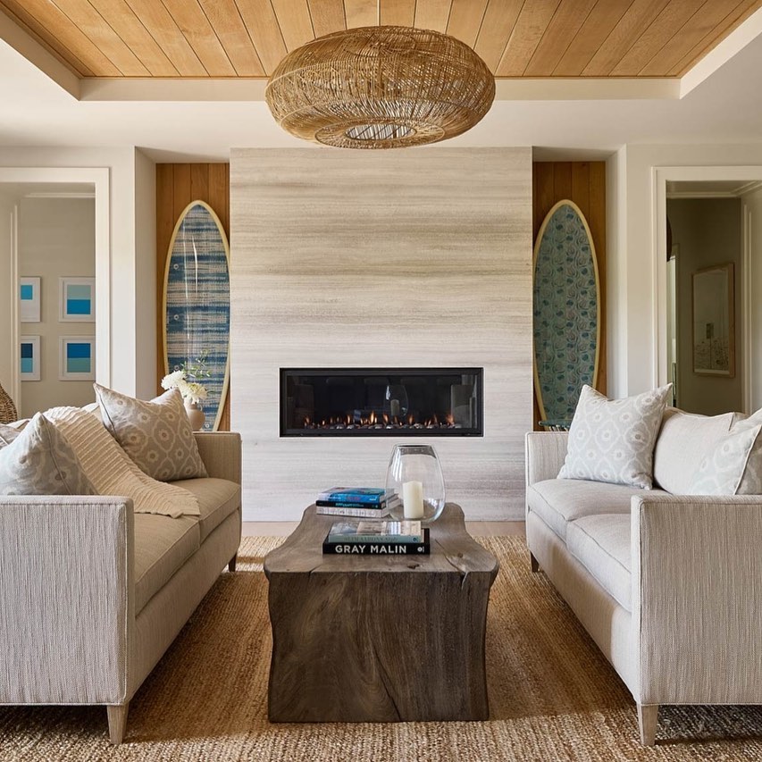 Coastal living room with linear fireplace, woven lighting, surfboard art, and natural textures