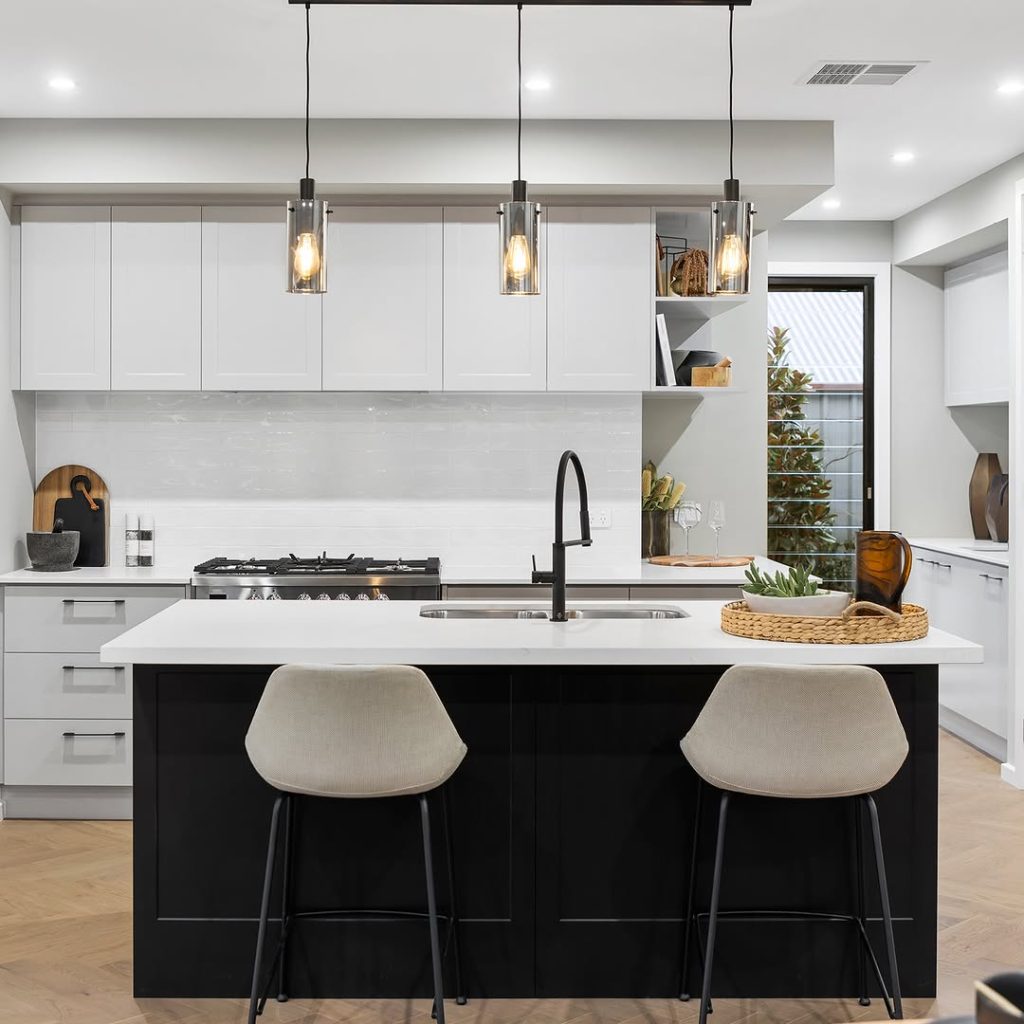 White kitchen with black island and glass pendant lights