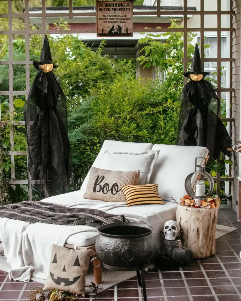 Outdoor patio with witch decorations, comfortable seating, and Halloween themed pillows
