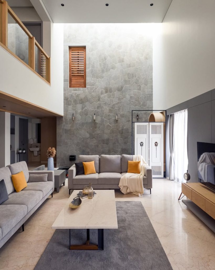 Double height living room with stone wall and orange accent pillows