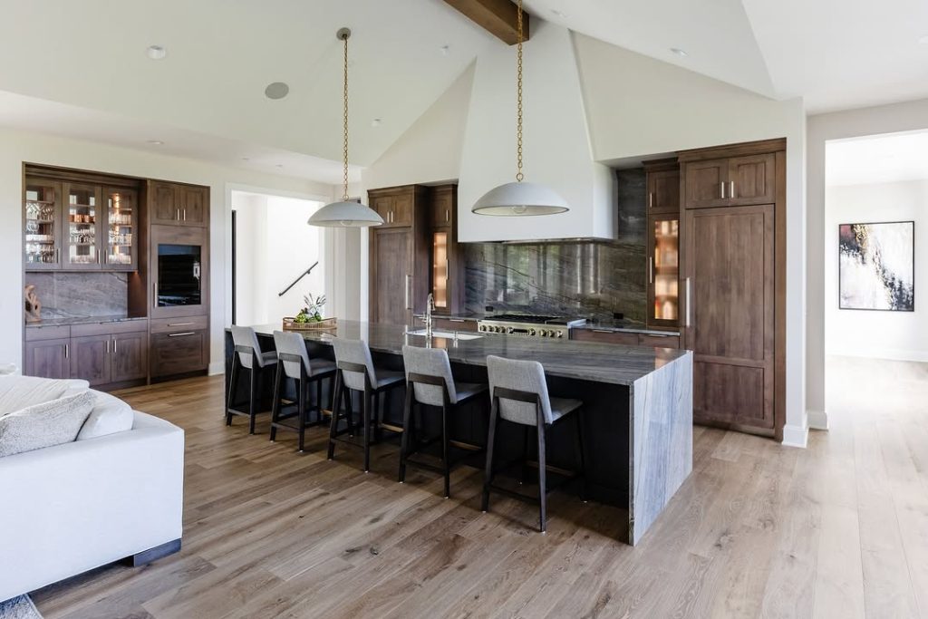 Kitchen with walnut cabinets, stone island, and vaulted ceiling