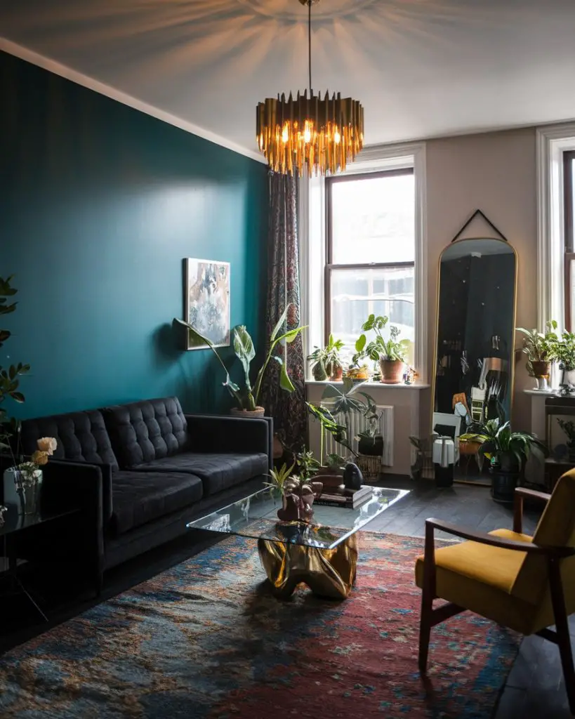 Black leather sofa with dramatic chandelier, teal walls, sculptural coffee table