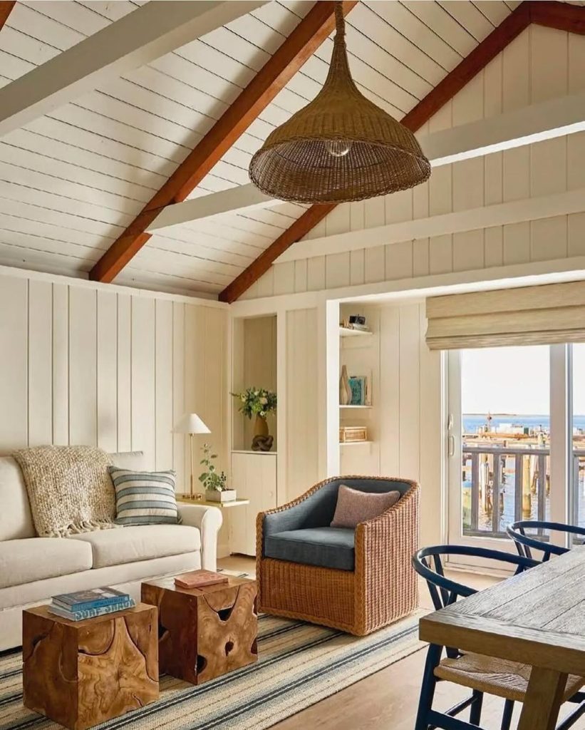 Coastal living room with woven pendant light, exposed beams, wicker furniture, and ocean views