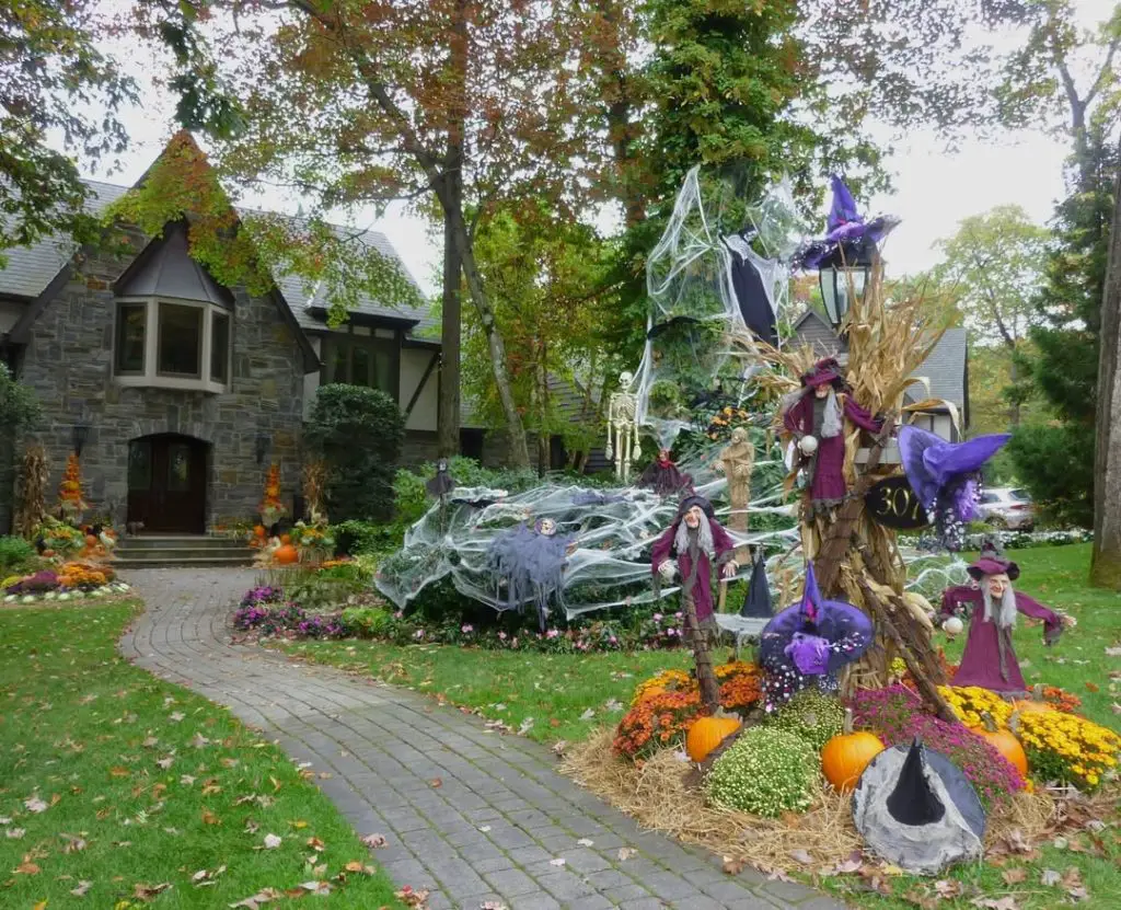 Large front yard Halloween display with witches, spider webs, and autumn decorations