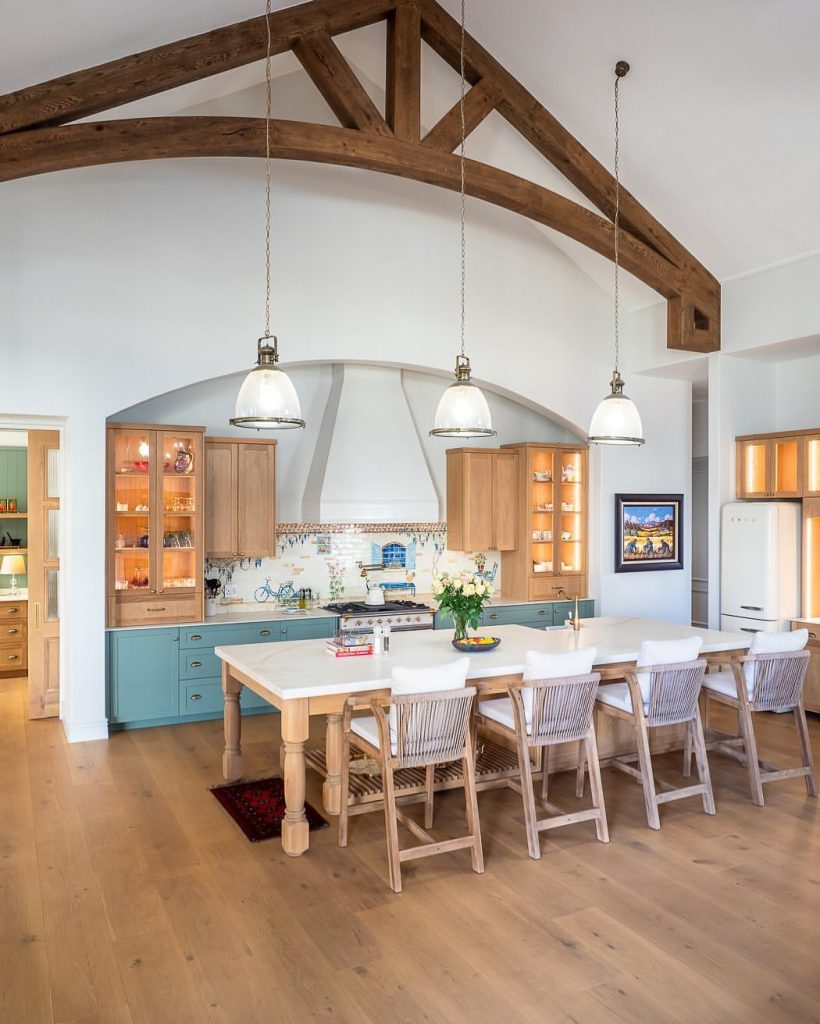 Farmhouse kitchen with exposed beams, sage cabinets, and decorative tile