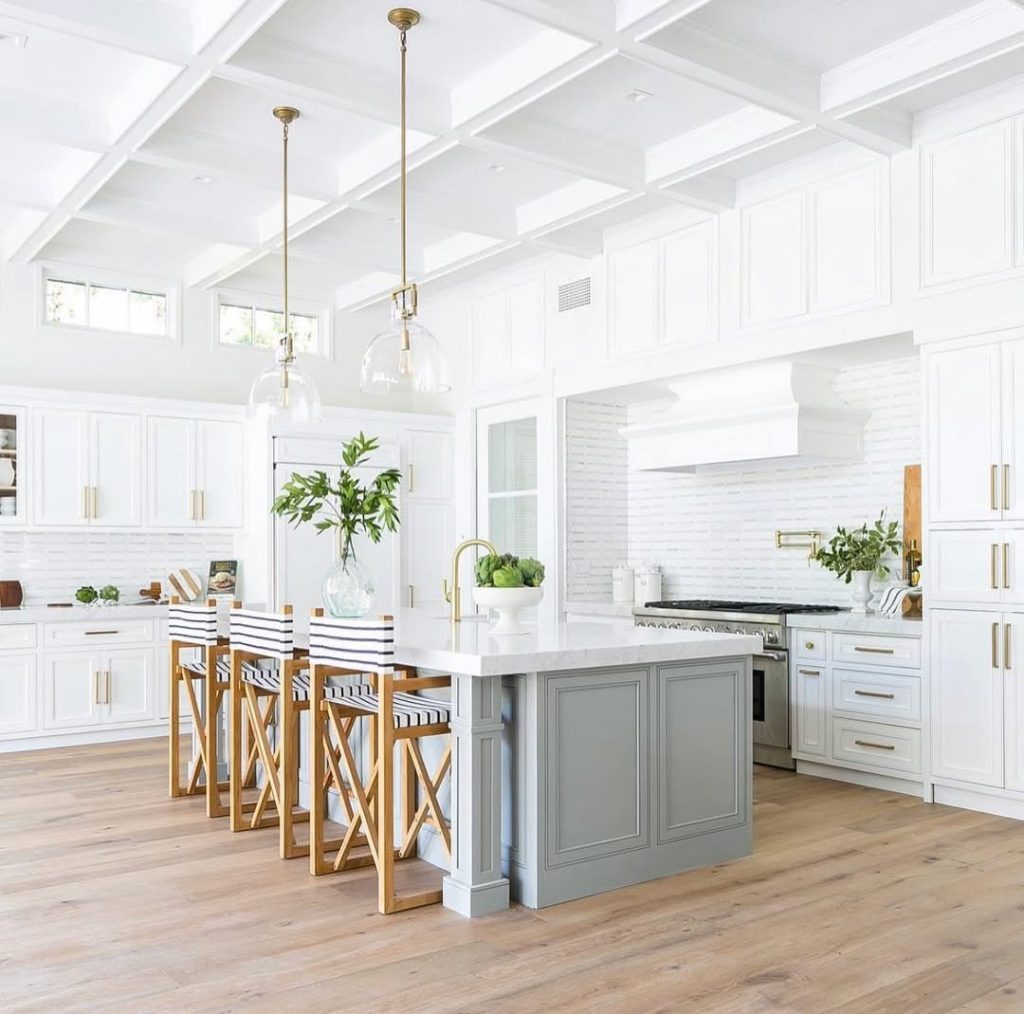 Kitchen with coffered ceiling, white cabinets, nautical rope bar stools, gray island base