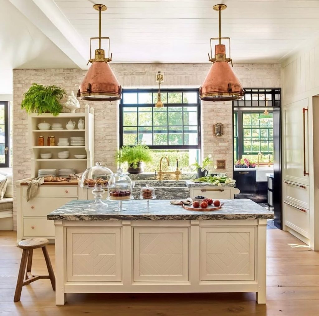 Kitchen with copper pendant lights, marble island, brick backsplash