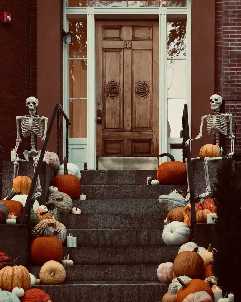 Two skeletons guarding front door with autumn pumpkins display