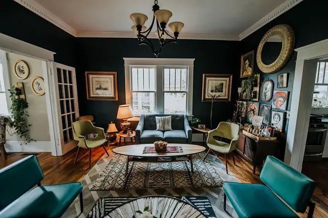 Green walls with vintage artwork, mixed furniture, cozy gallery style