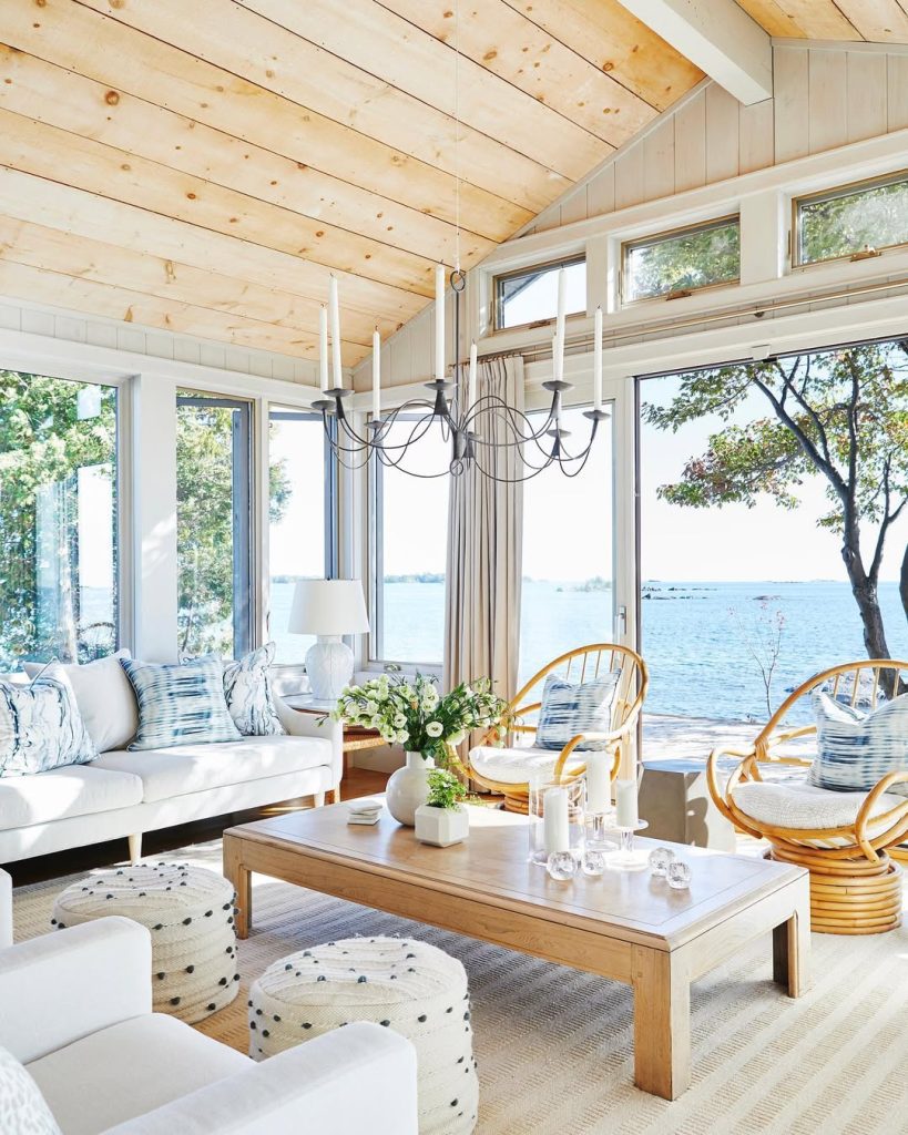 Lakefront living room with floor-to-ceiling windows, wood ceilings, modern chandelier, and lake views