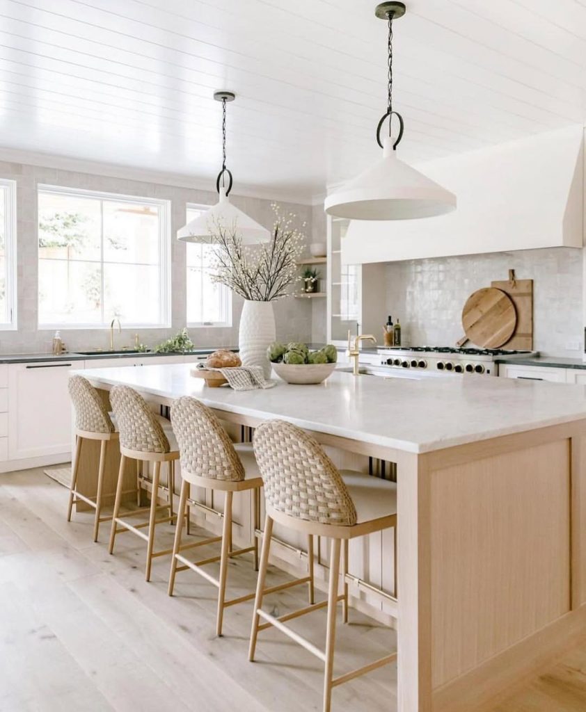 Neutral kitchen with woven bar stools, white shiplap ceiling, brass fixtures, wood island