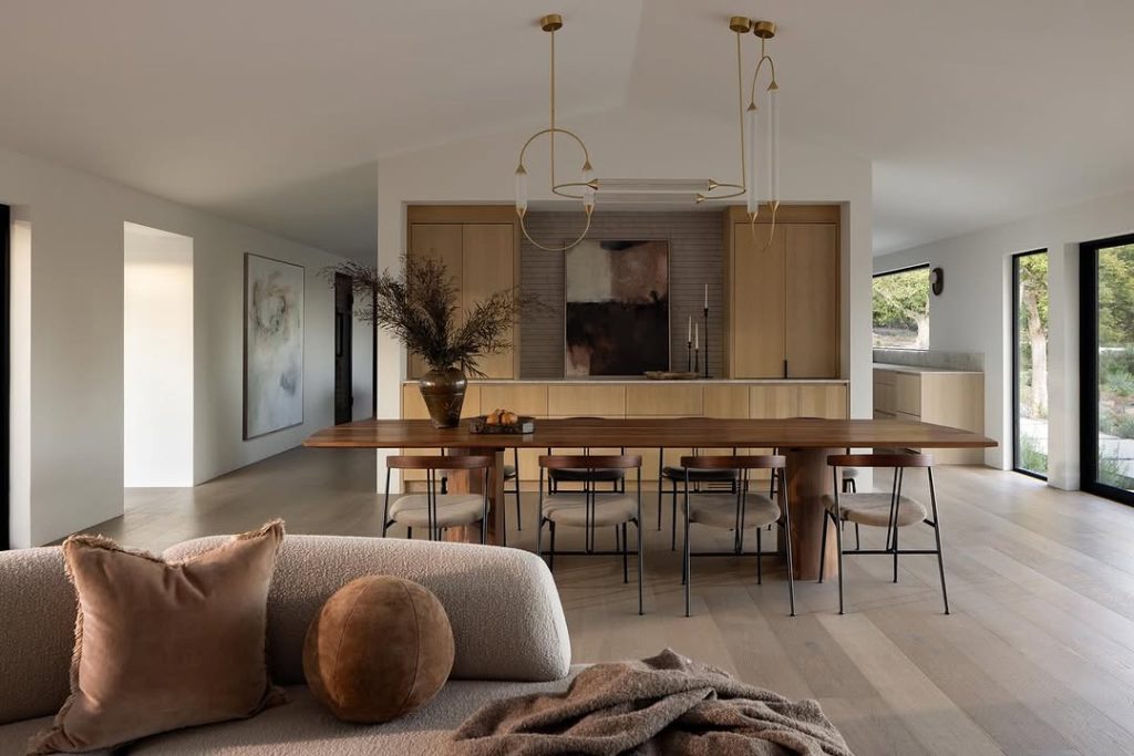Open kitchen with brass fixtures, neutral tones, and dining area